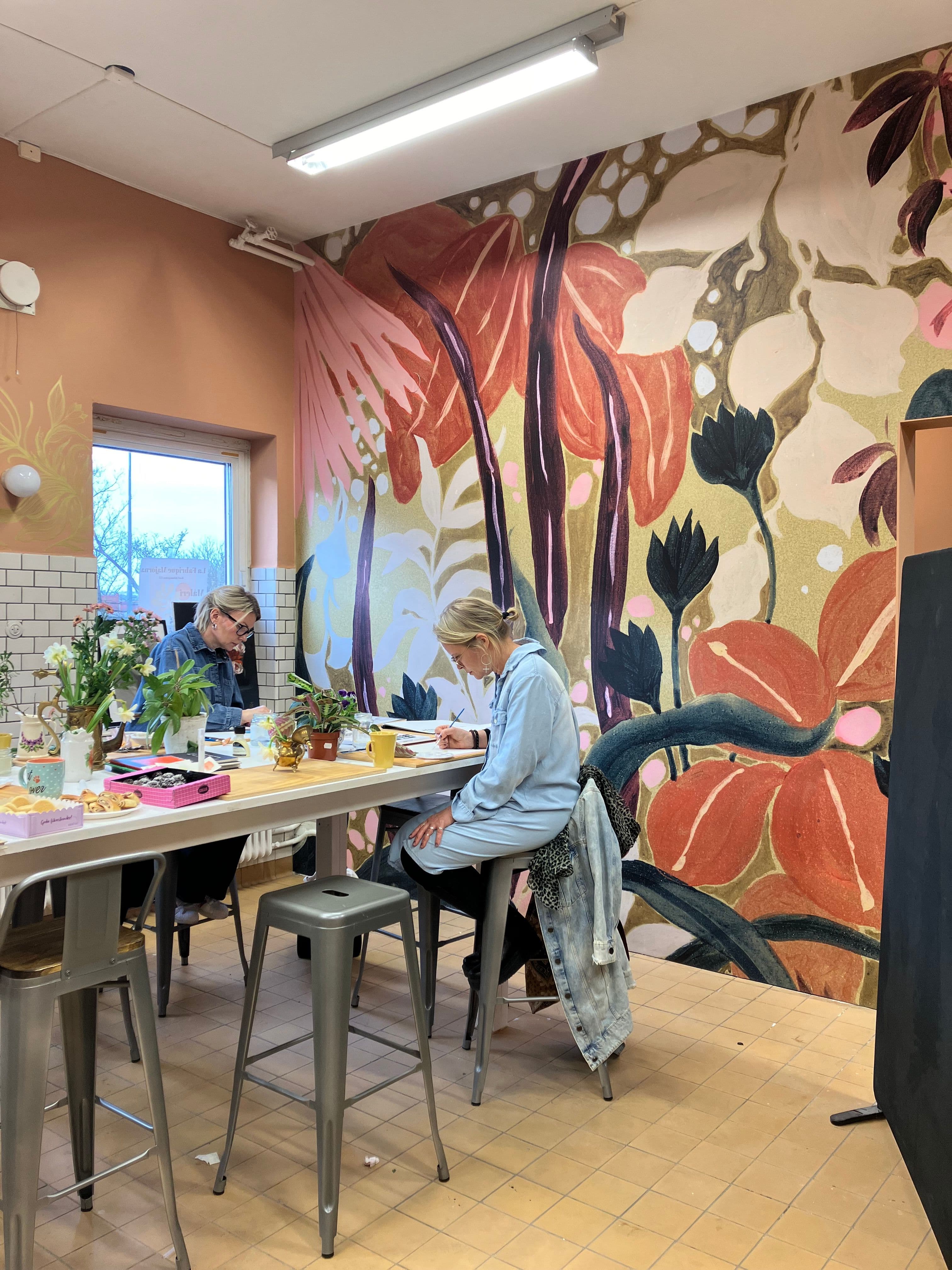 Personer som målar framför en vacker tapet